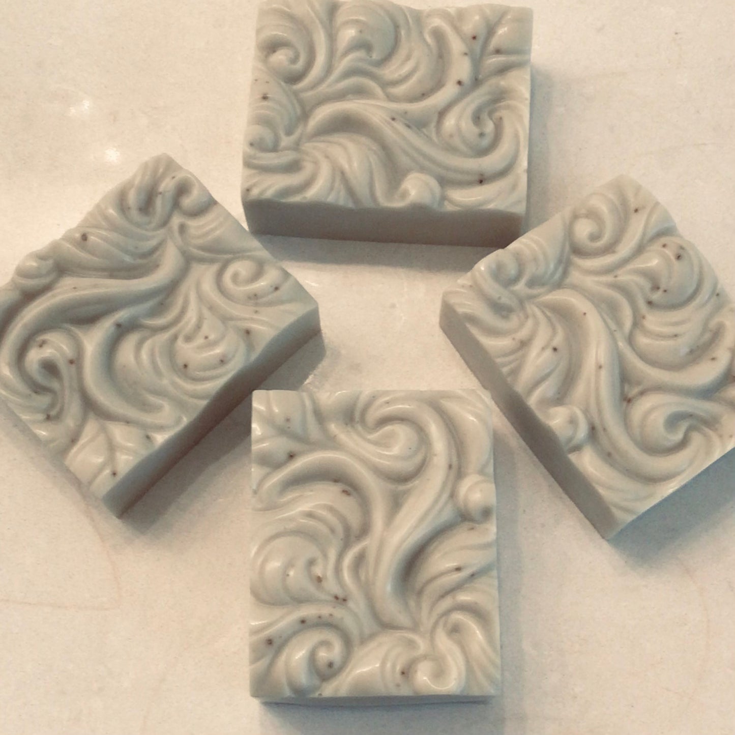 Handcrafted French Green Clay Facial Bars collection on white marble with botanicals — The Clay Collection | Handcrafted Soaps by SynEb