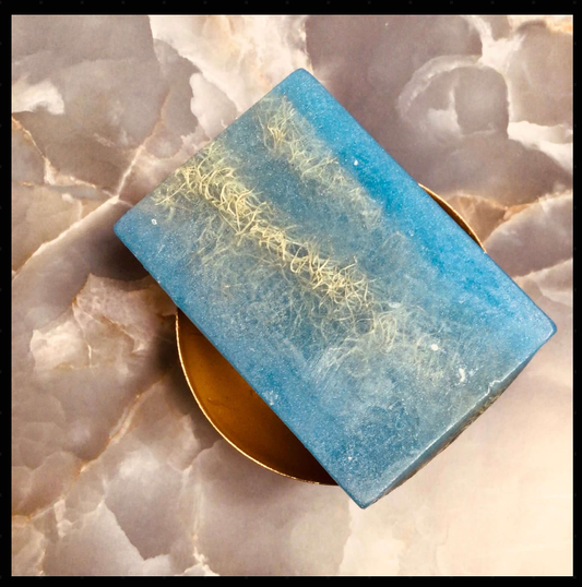 Handcrafted Soaps by SynEb Embedded Organic Exfoliating Glycerin Bar in blue on a gold dish with rose quartz — luxury loofah fruit soap